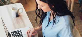  Woman is sitting in front of a table and using laptop