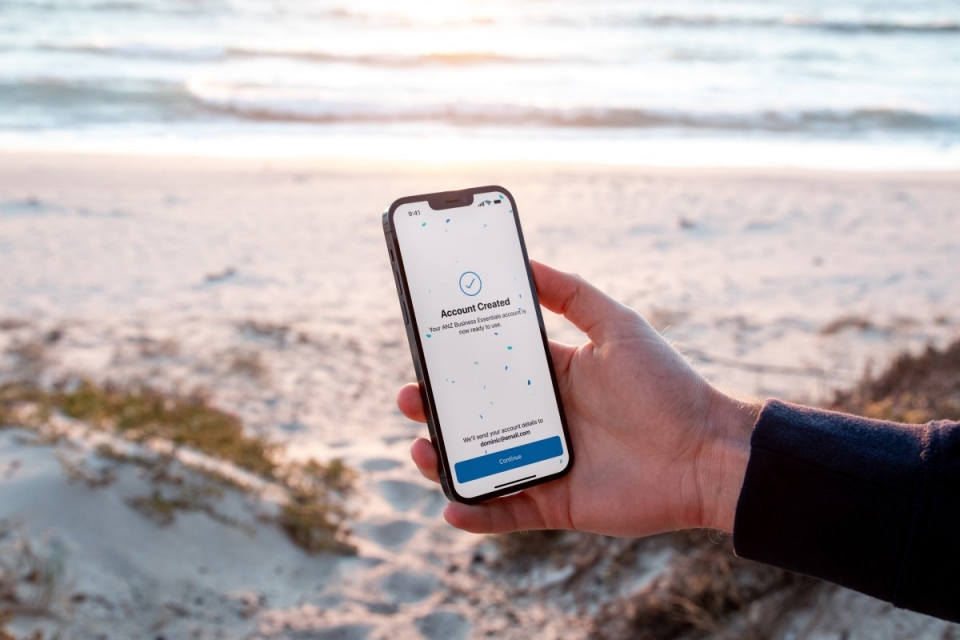 outstretched hand of person at the beach holding phone with account information on it 
