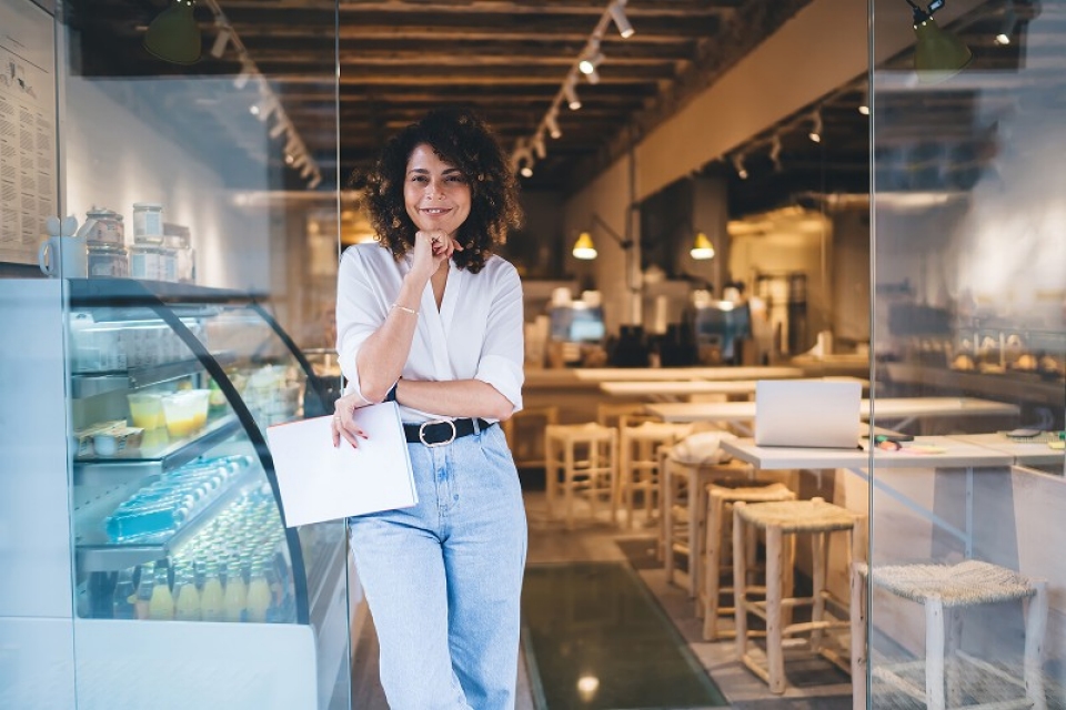Female business owner standing in doorway of cafe