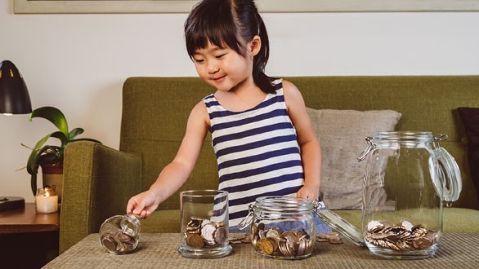 Young girl putting coins in jars