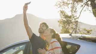 Couple taking selfie in front of car